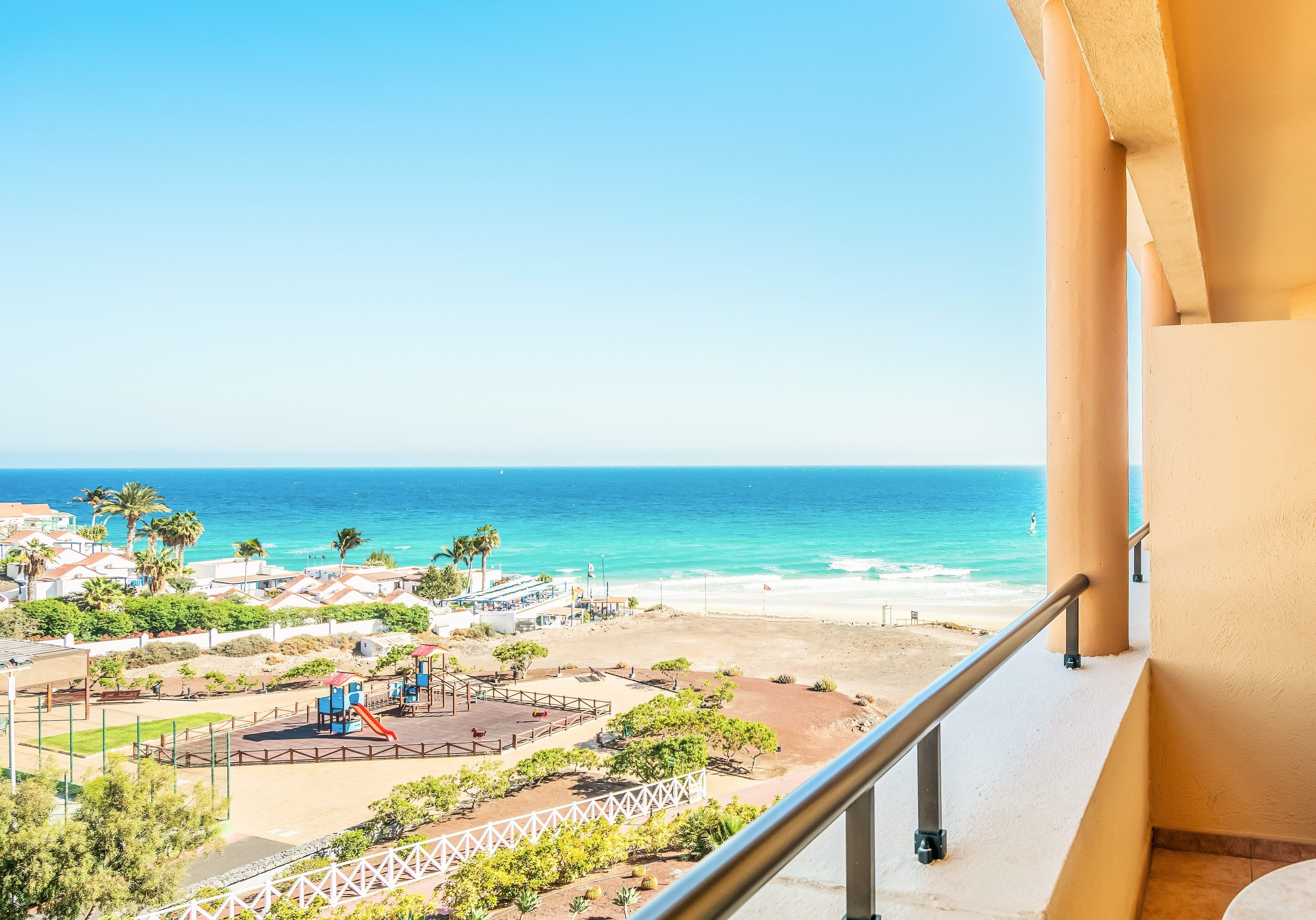 A balcony with a view of the beach and ocean.