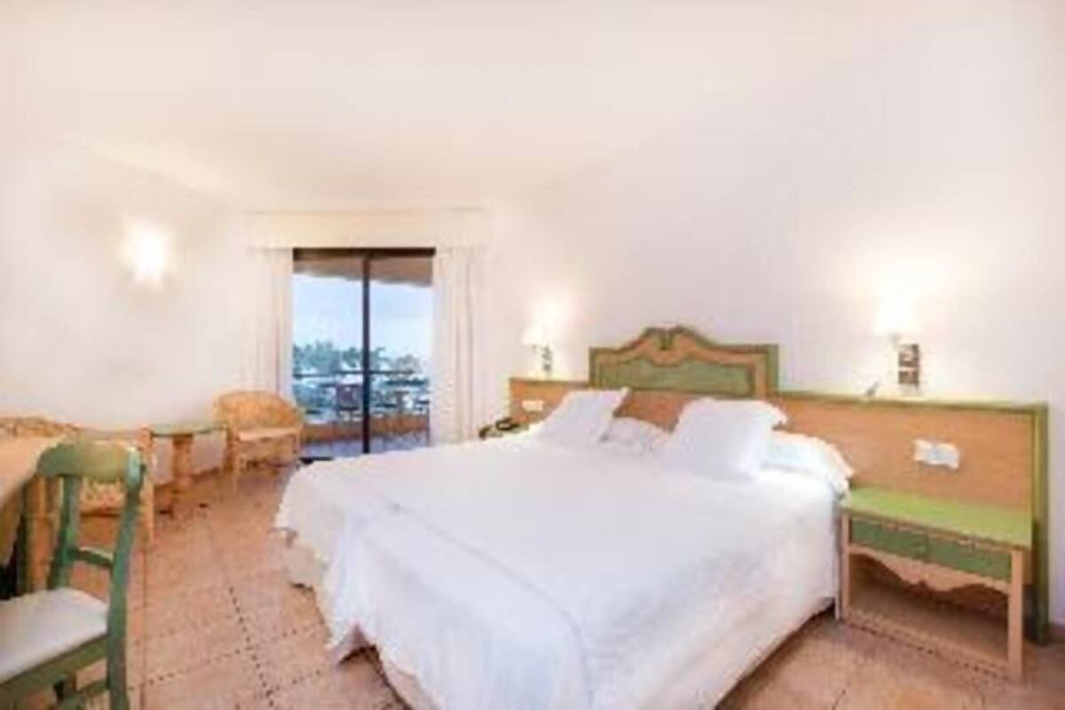 A hotel room with a bed, a chair, a nightstand, and a window with a view.