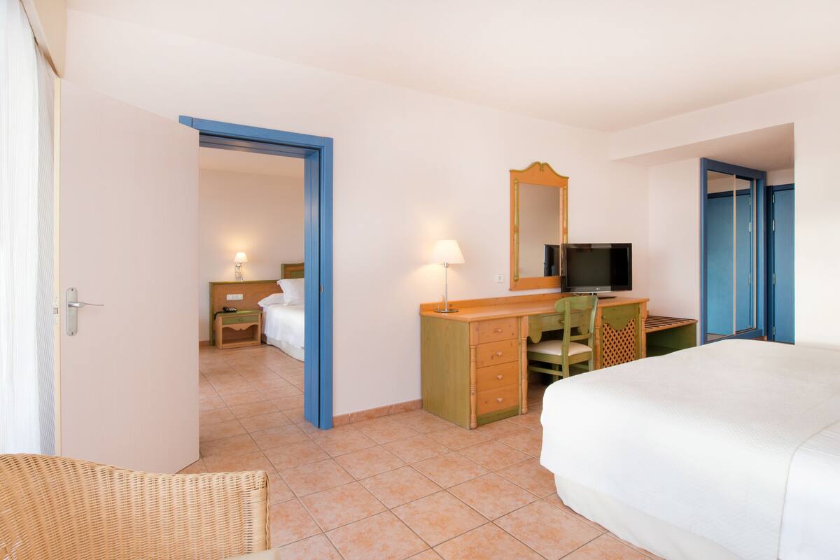 A hotel room with a bed, a desk with a chair, a television, and a wardrobe.