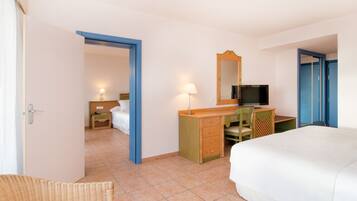 A hotel room with a bed, a desk with a chair, a television, and a wardrobe.