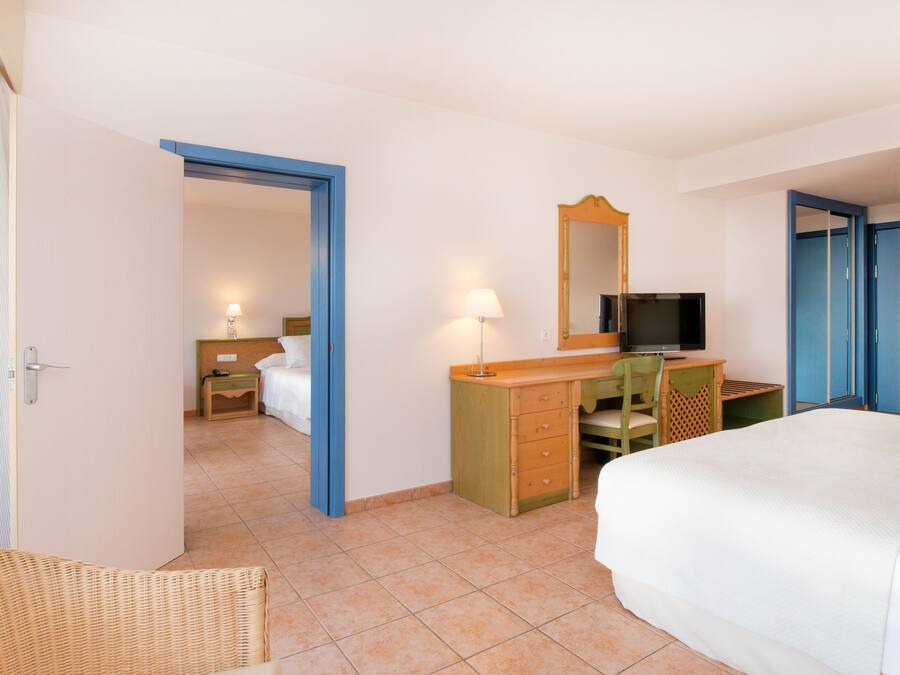 A hotel room with a bed, a desk with a chair, a television, and a wardrobe.