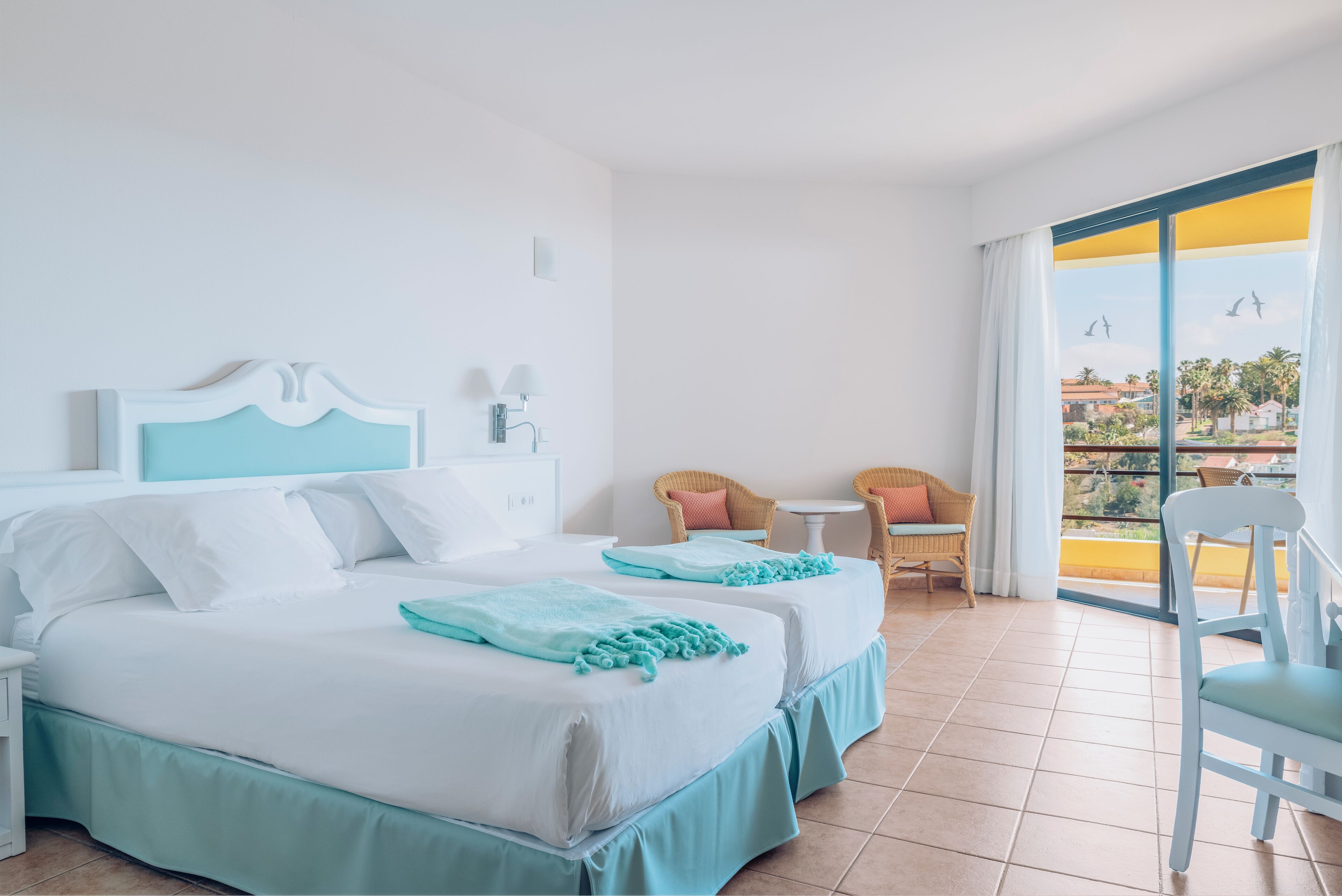 Habitación de hotel con dos camas, un balcón y vista a la ciudad.
