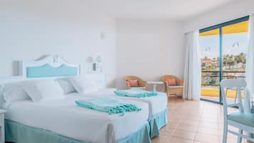 Habitación de hotel con dos camas, un balcón y vista a la ciudad.