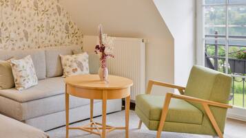Une pièce chaleureuse avec un canapé, une table ronde en bois et un fauteuil vert.
