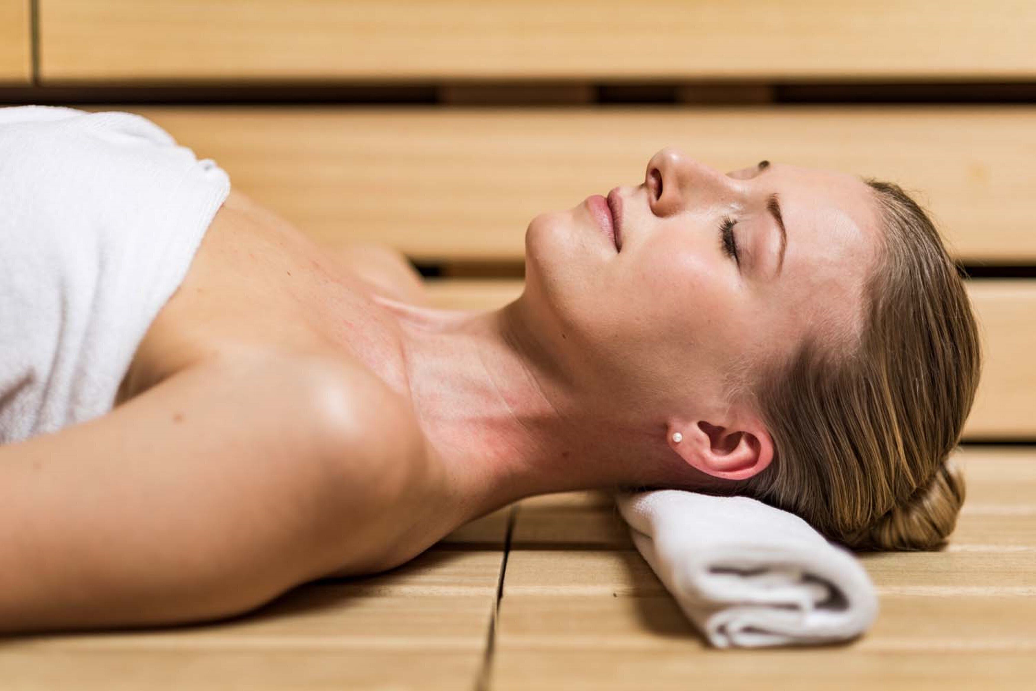 A person lying on a wooden floor with a towel draped over their shoulder.