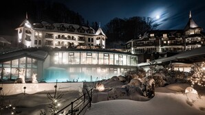 Un hotel grande e iluminado con fachada de vidrio, paisajes nevados y una torre destacada.