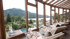 Zona de spa con sillones reclinables y vistas a un lago y montañas.
