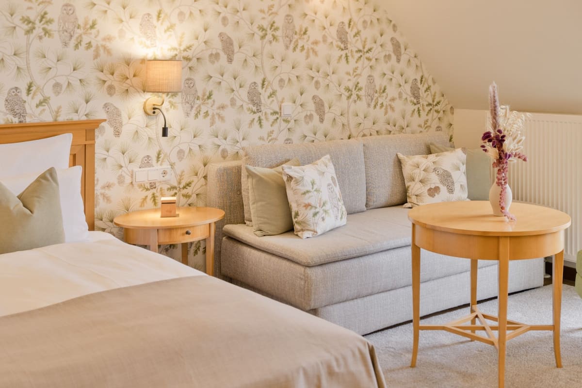Une chambre à coucher avec un lit, un canapé, une petite table et une lampe.