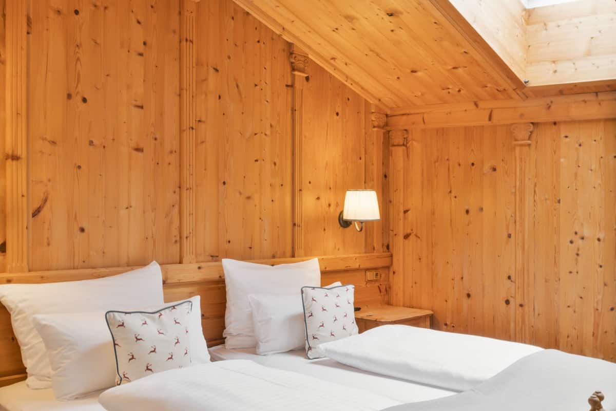 Une pièce en bois avec un lit, des oreillers et une table de chevet.