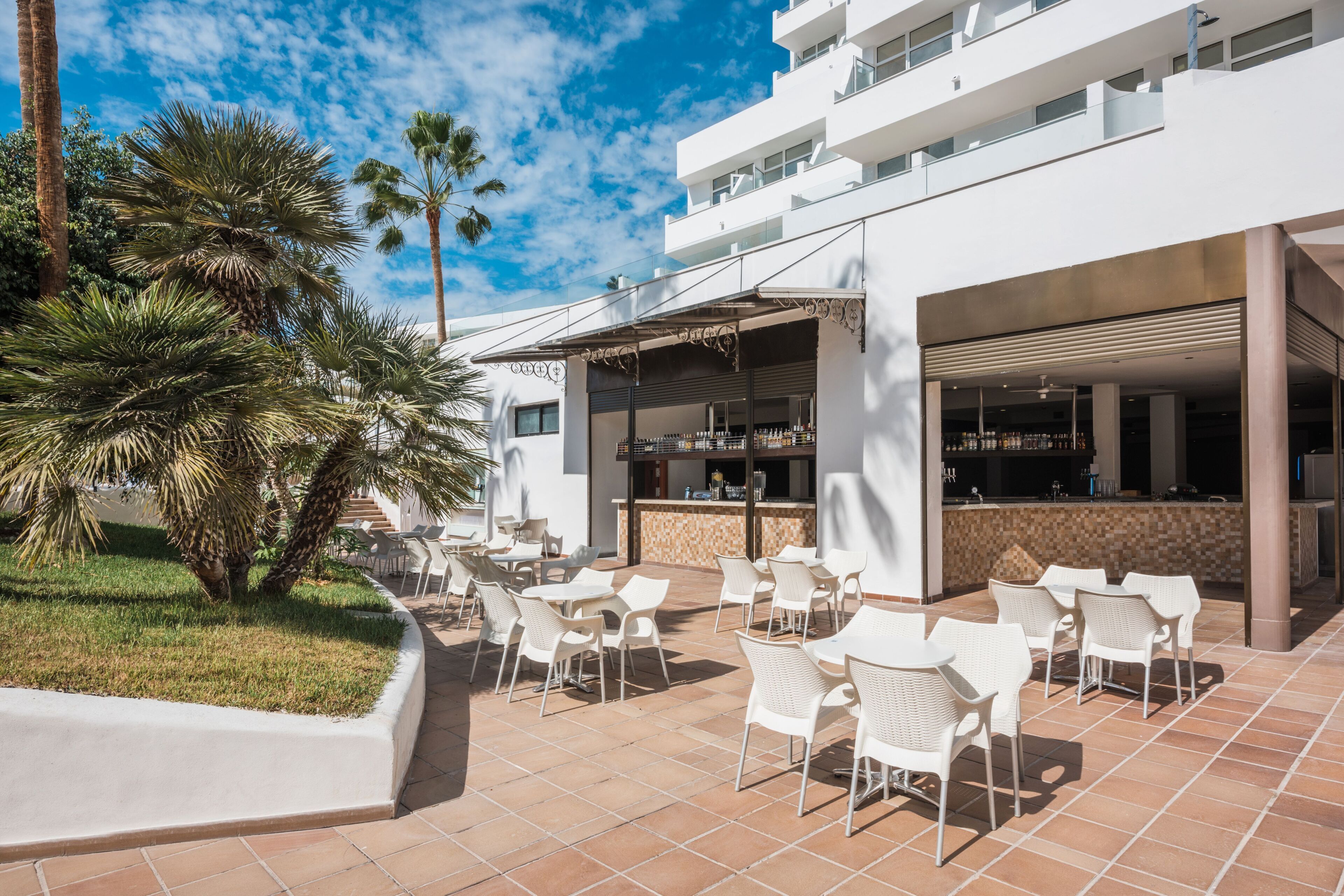 An outdoor patio with white chairs and a bar area.