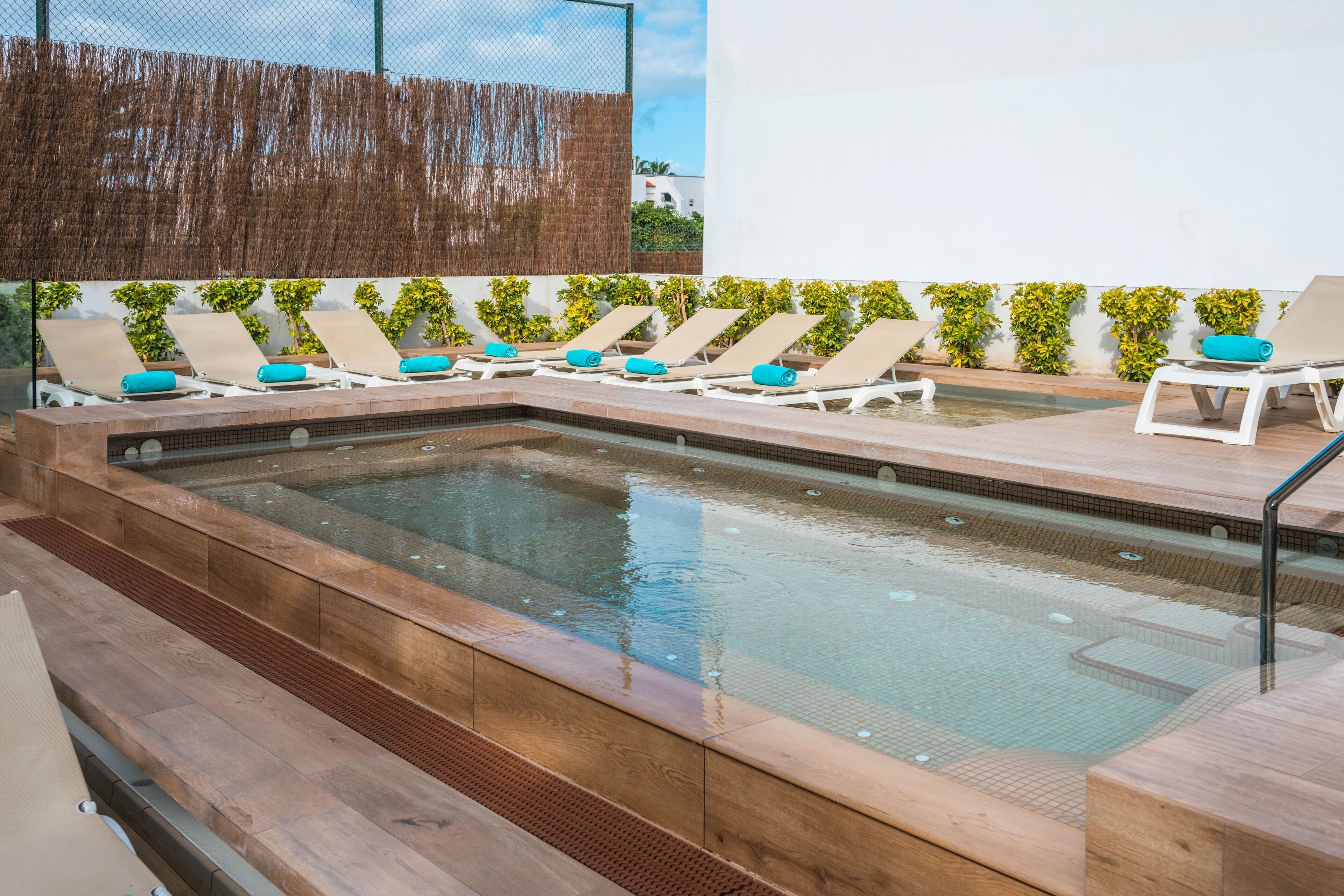 A swimming pool with lounge chairs and a wooden deck.