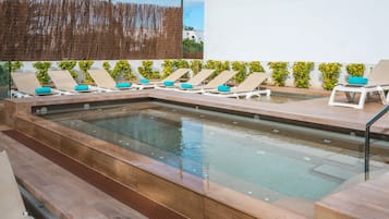 A swimming pool with lounge chairs and a wooden deck.