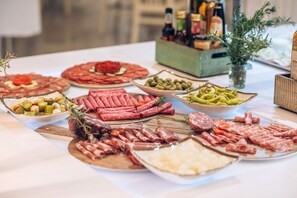 A table with various types of cured meats and cheeses, accompanied by olives and pickles.