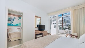 A hotel room with a bed, a desk with a television, a chair, and a balcony with a view of a building. - Iberostar Waves Las Dalias -All Inclusive (Adeje)