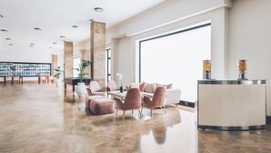 A spacious lobby with a reception desk, seating area, and a large window providing natural light. - Iberostar Waves Las Dalias -All Inclusive (Adeje)