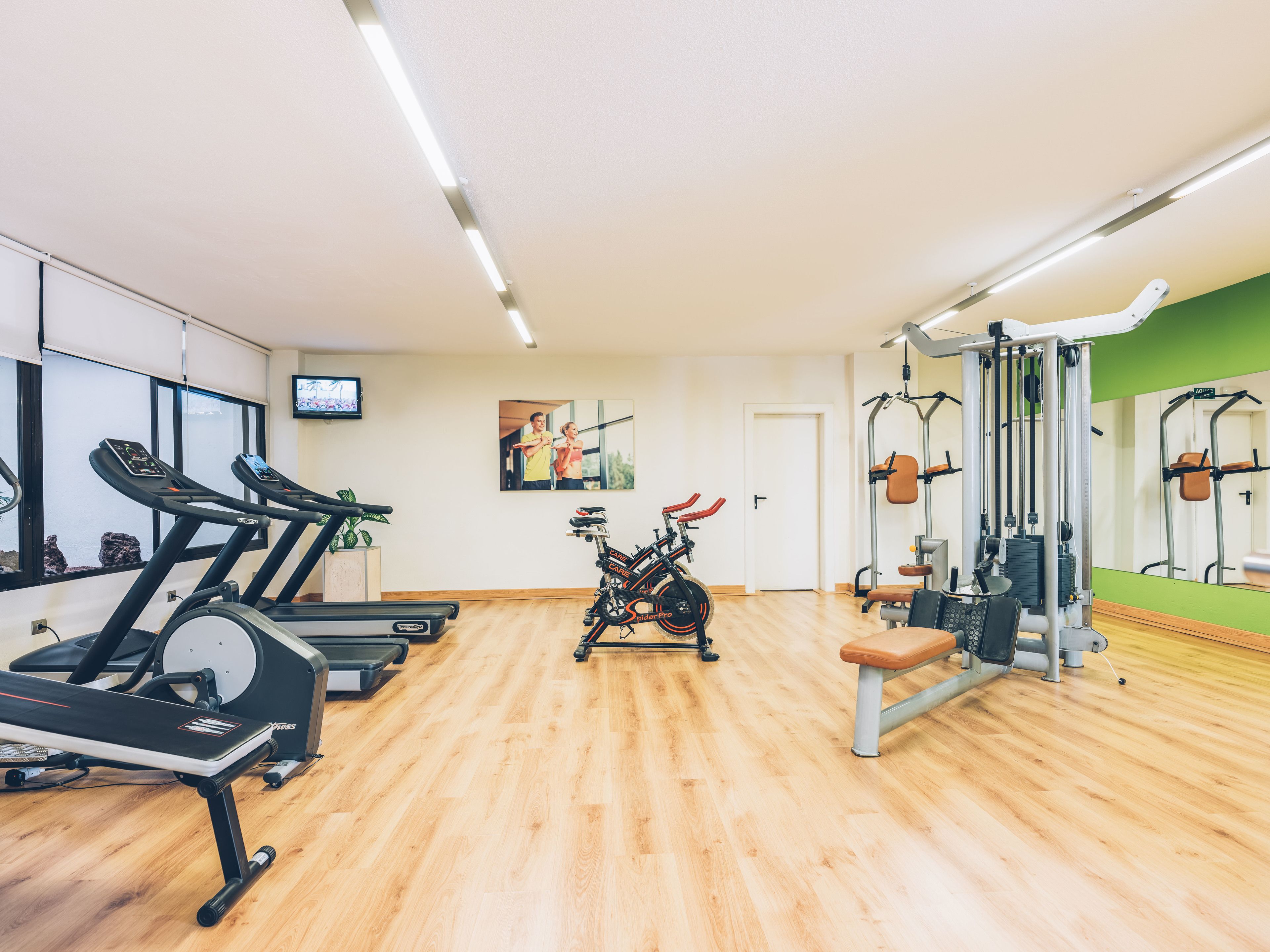 Un gimnasio con cintas de correr, una bicicleta estática y equipo de levantamiento de pesas.