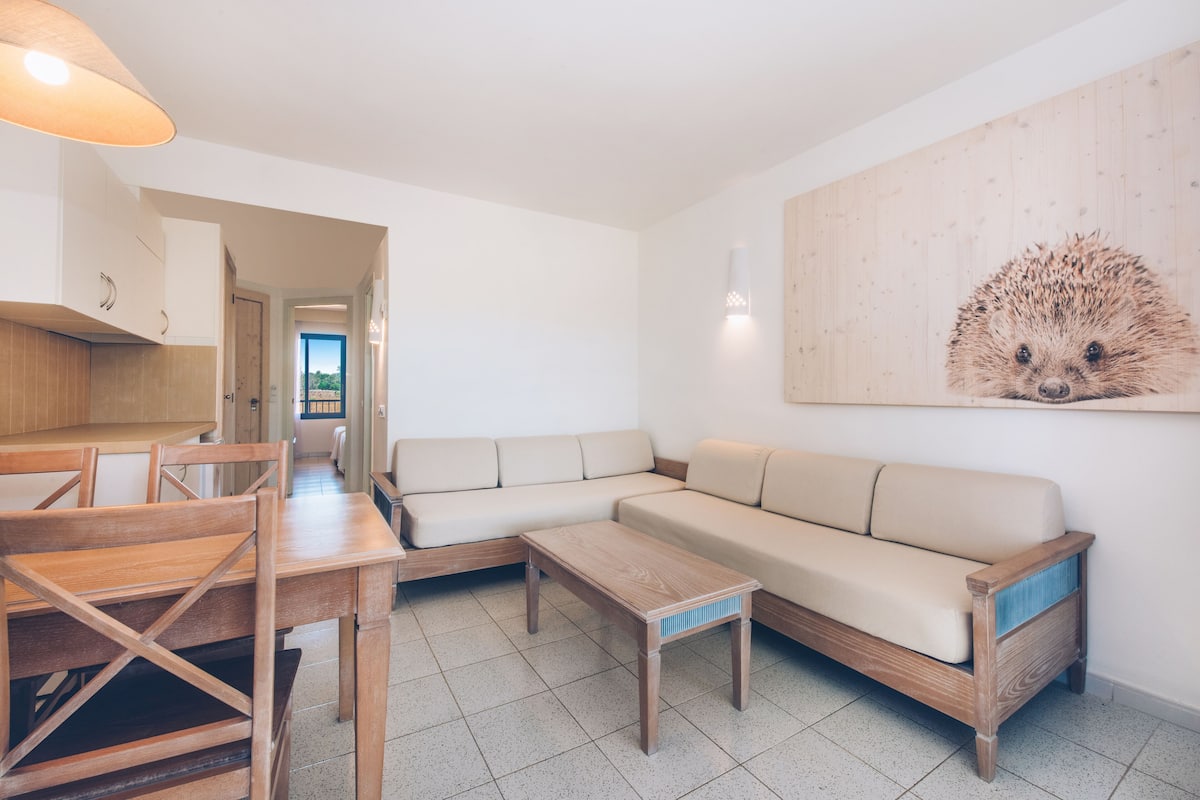A modern living room with a sofa, wooden coffee table, and dining area with chairs.