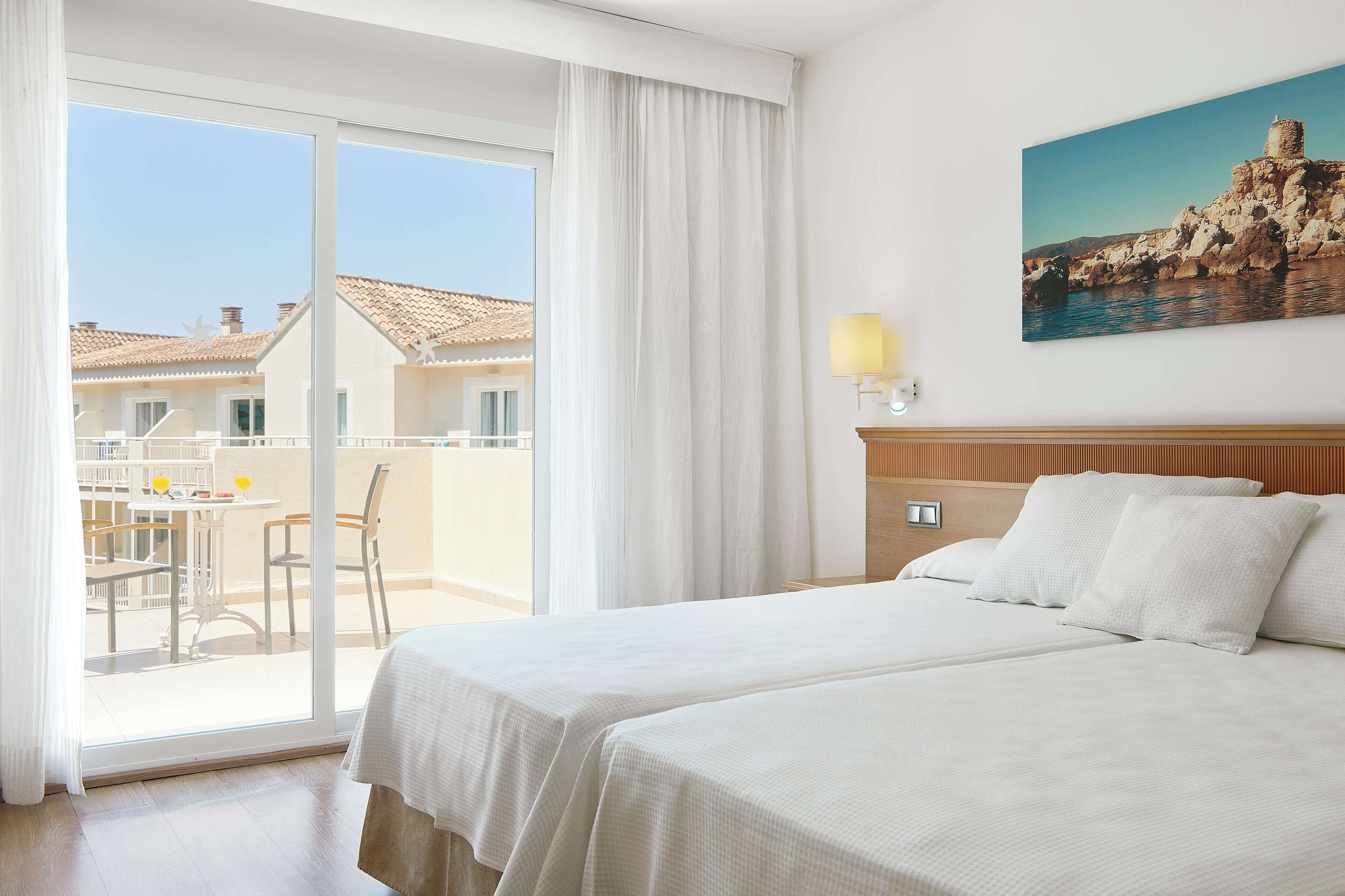 Une chambre d’hôtel dotée d’une grande porte-fenêtre coulissante donnant sur un espace extérieur aménagé pour se détendre.