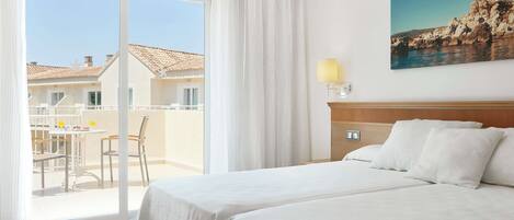 Une chambre d’hôtel dotée d’une grande porte-fenêtre coulissante donnant sur un espace extérieur aménagé pour se détendre.