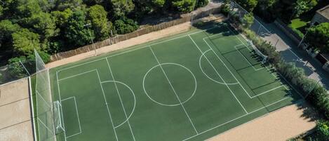 An aerial view of a tennis court surrounded by dense trees.