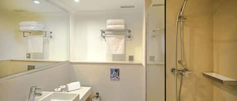 A modern bathroom with a sink, mirror, toilet, and shower.
