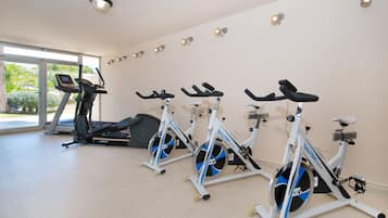 Un gimnasio con bicicletas estáticas, una cinta de correr y un amplio ventanal con vistas al verdor.