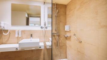 Un baño moderno con cabina de ducha de vidrio, un lavabo blanco y un espejo sobre él.