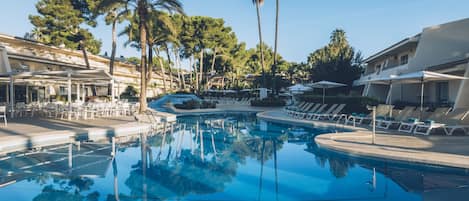 Una piscina al aire libre, sombrillas, sillones reclinables de piscina