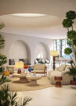 Ein modernes Wohnzimmer mit einem runden Couchtisch, Sofas und Blick ins Freie.