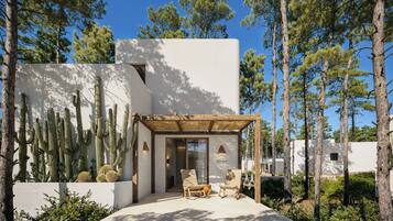 A modern building with a patio area featuring two rocking chairs and a wooden pergola.