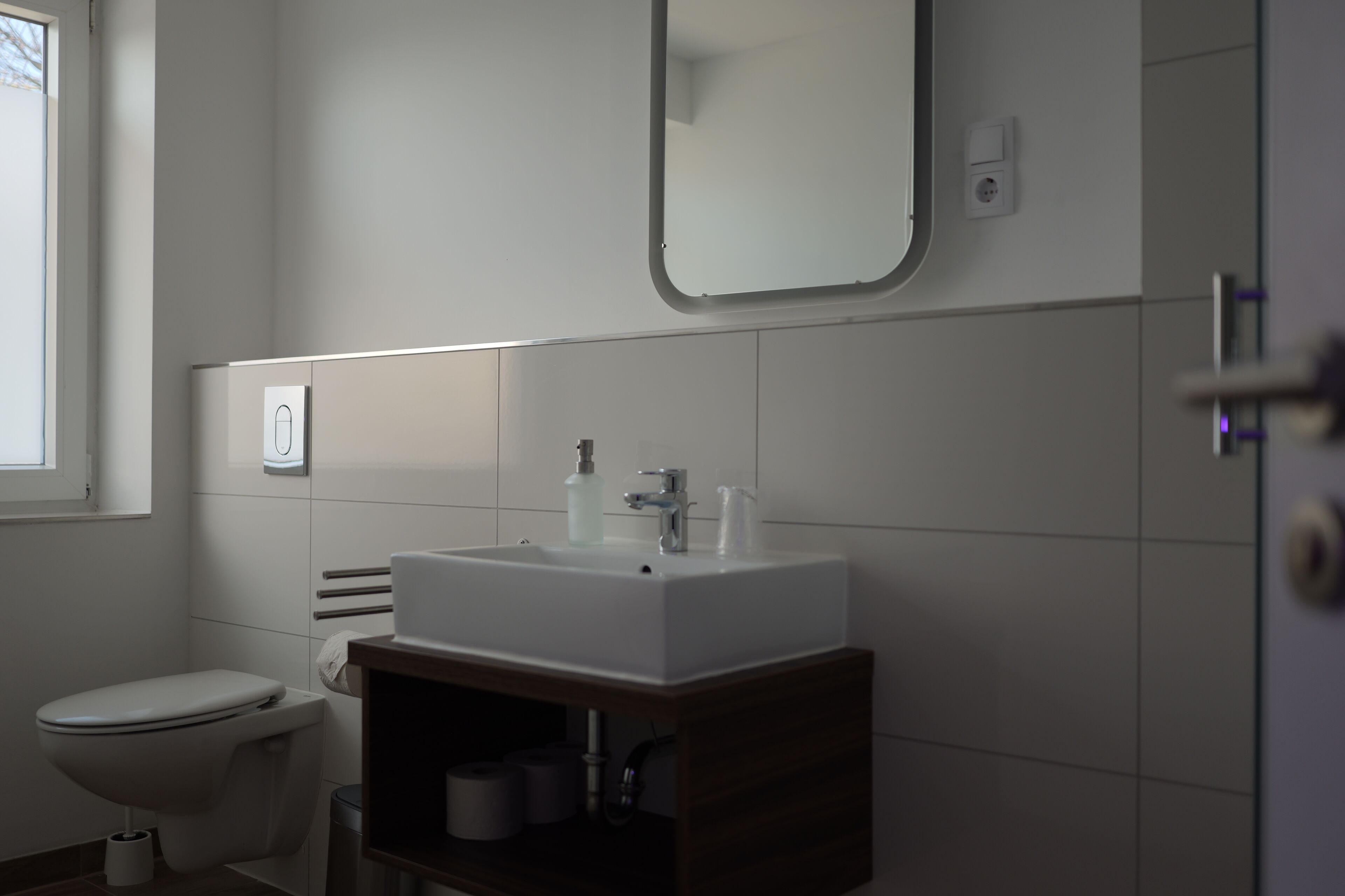 Baño con lavamanos, espejo y retrete blancos.