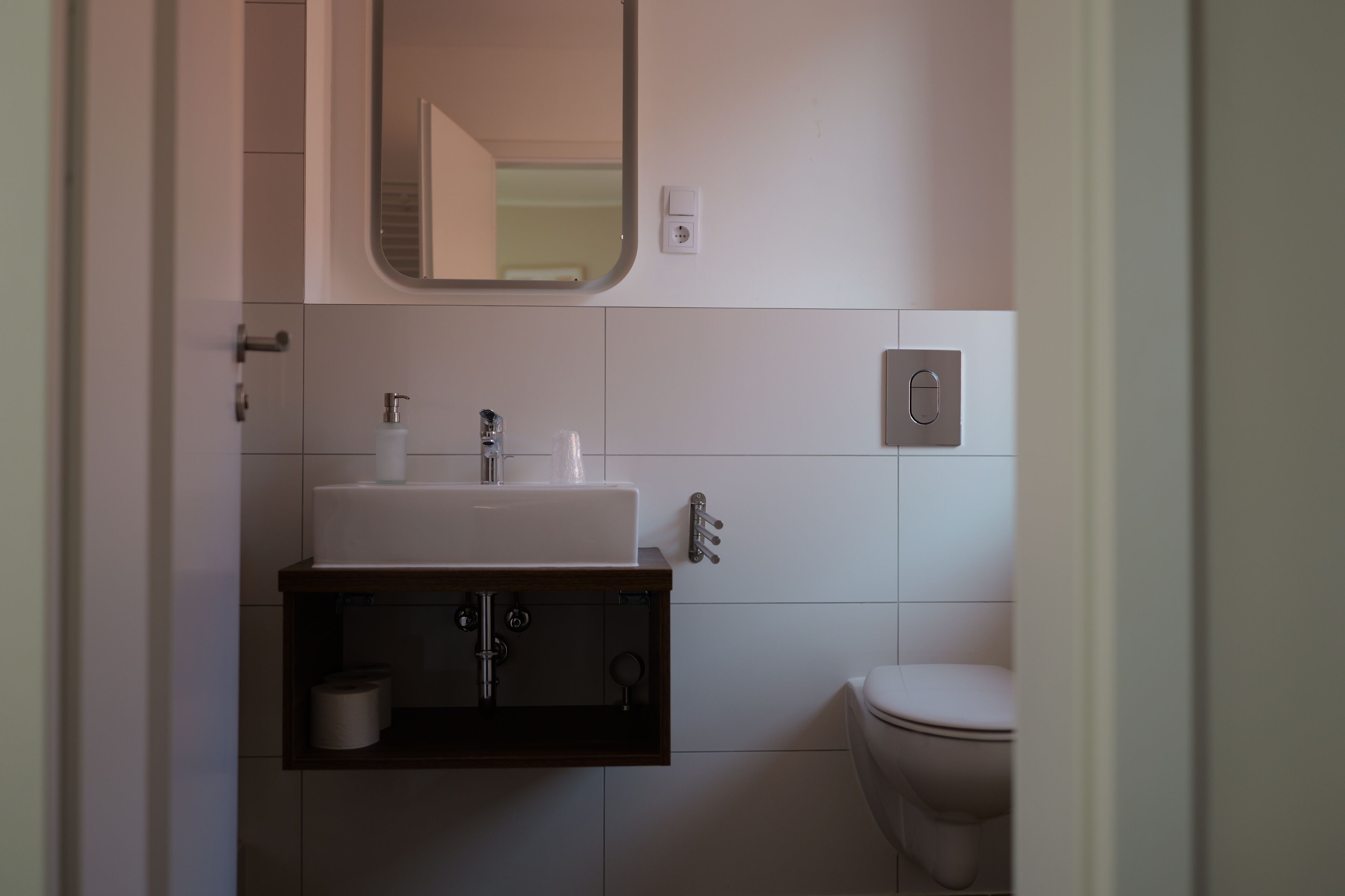 Un baño con un lavabo blanco, un espejo, un inodoro y un perchero para toallas.