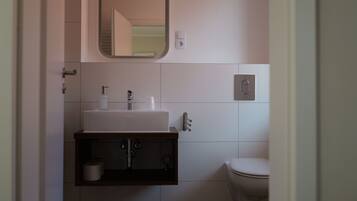 Un baño con un lavabo blanco, un espejo, un inodoro y un perchero para toallas.