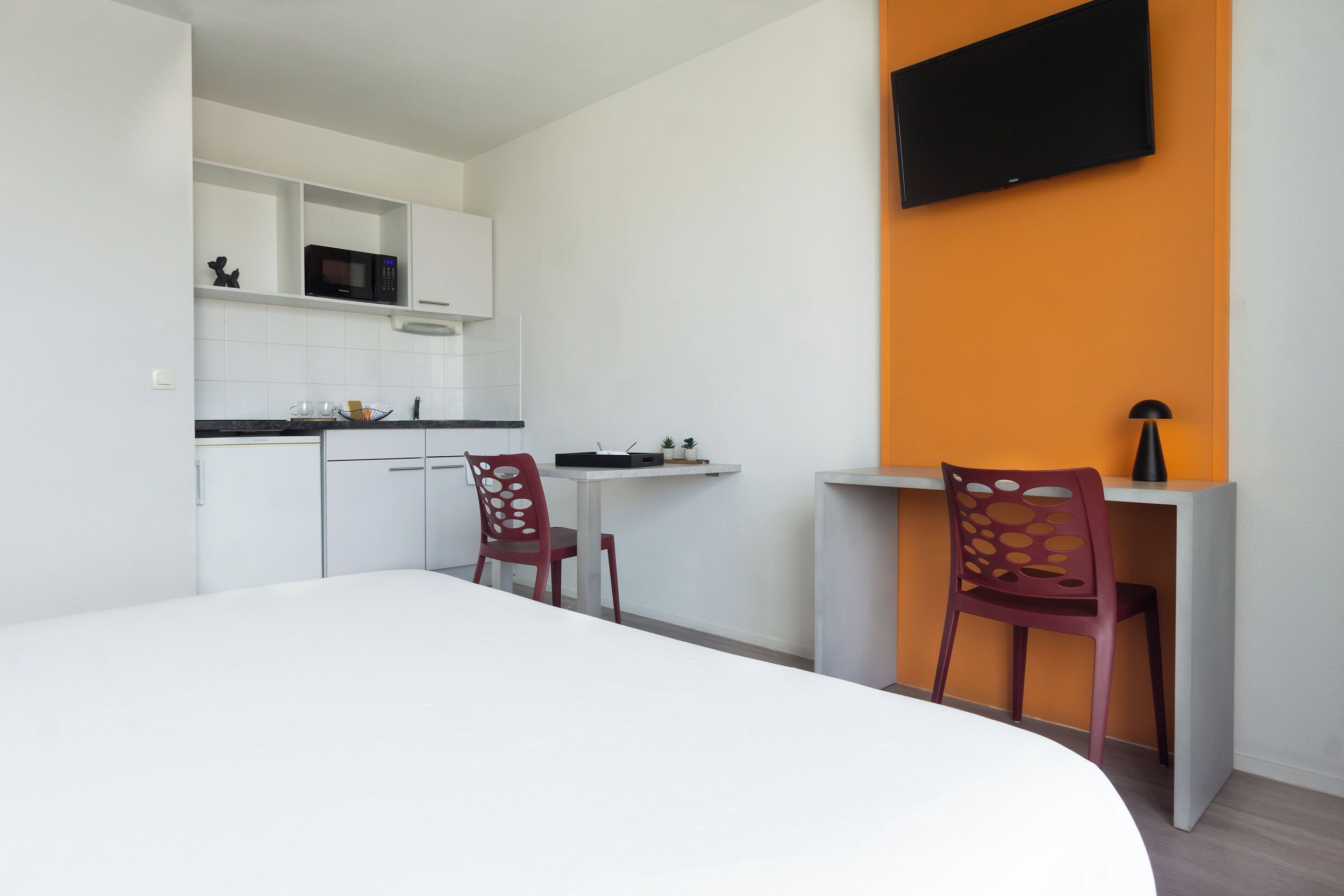 Una cocina moderna con armarios blancos, un microondas y un comedor con una mesa y dos sillas.