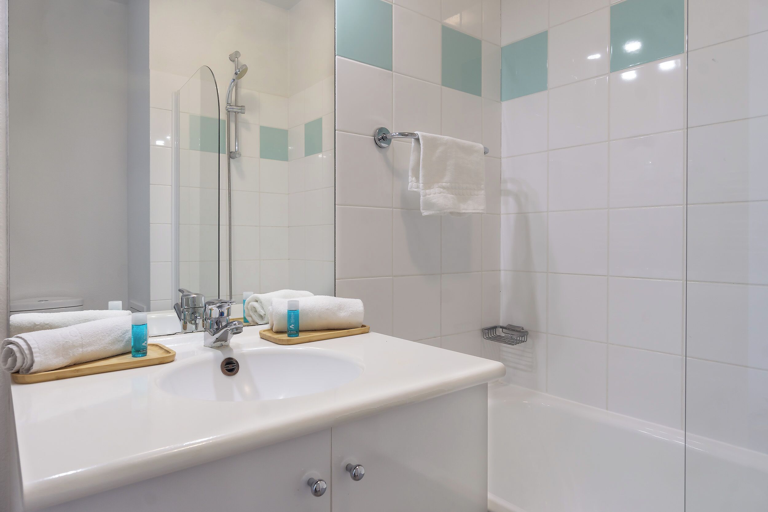 Een badkamer met een wastafel, spiegel en douche.