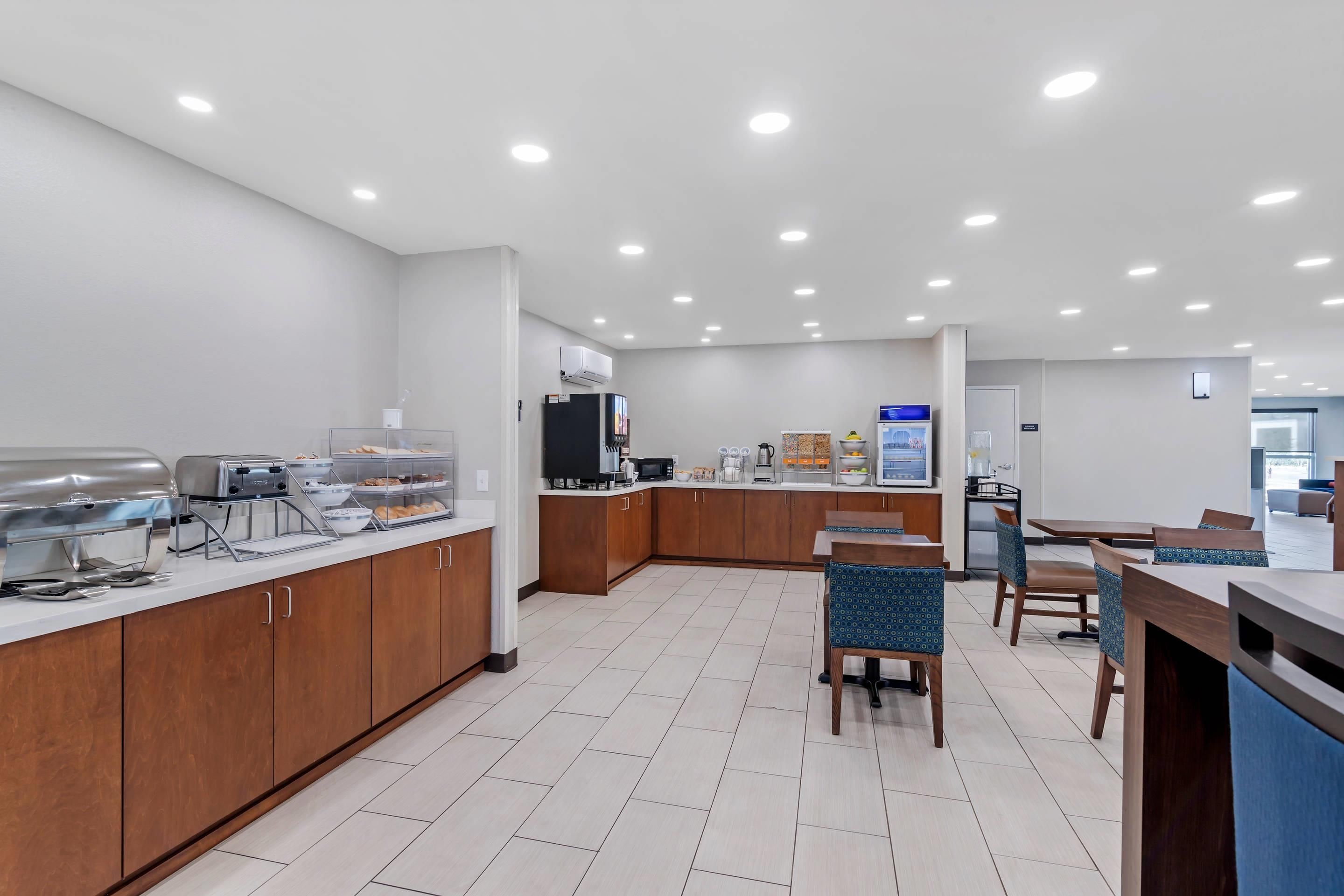A modern kitchen with a buffet setup, wooden cabinets, and a dining area with chairs and a table.