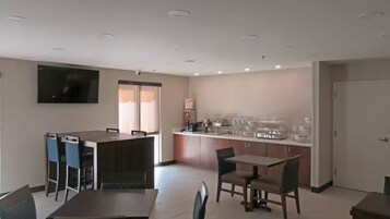 Una habitación de hotel moderna con zona de comedor, cocina, televisor de pantalla plana y un ventanal grande.
