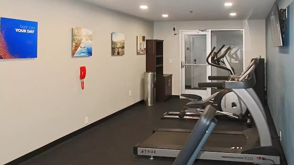 A gym with treadmills, a wall-mounted phone, and motivational posters.