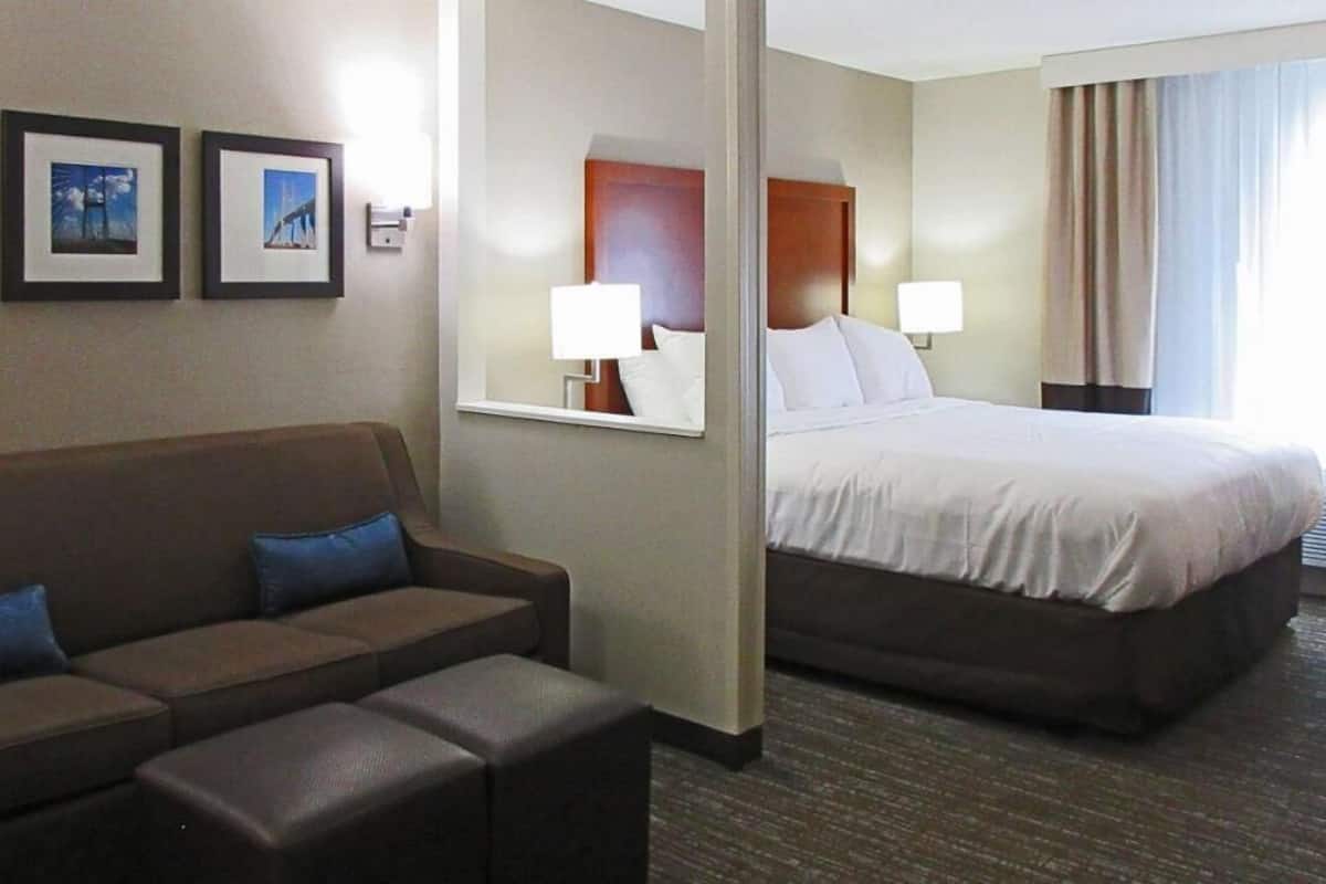 A hotel room with a bed, a sofa, and a mirror.