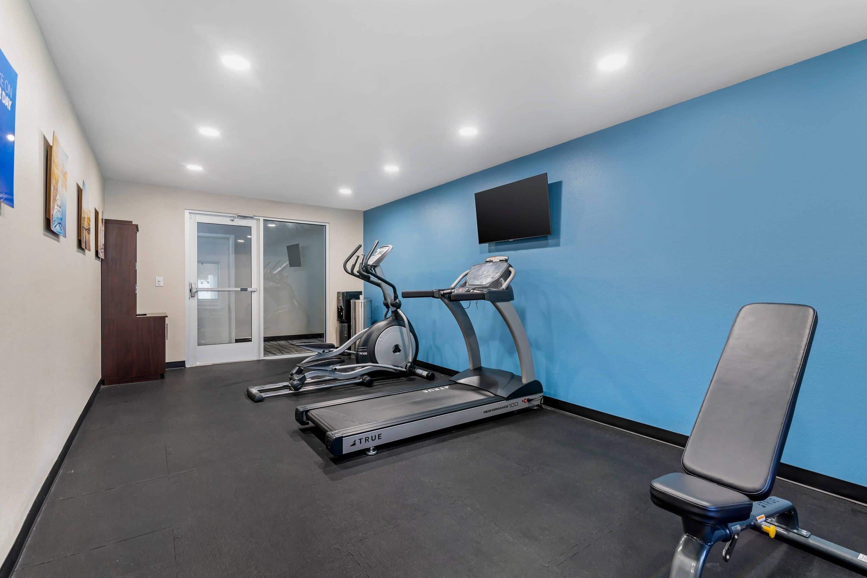 A fitness room with treadmills, a stationary bike, and a bench.
