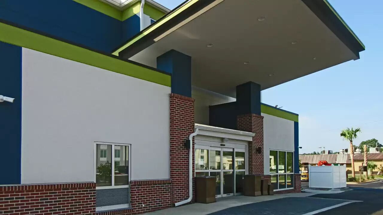 A modern building with a glass entrance, a covered area, and a brick base.