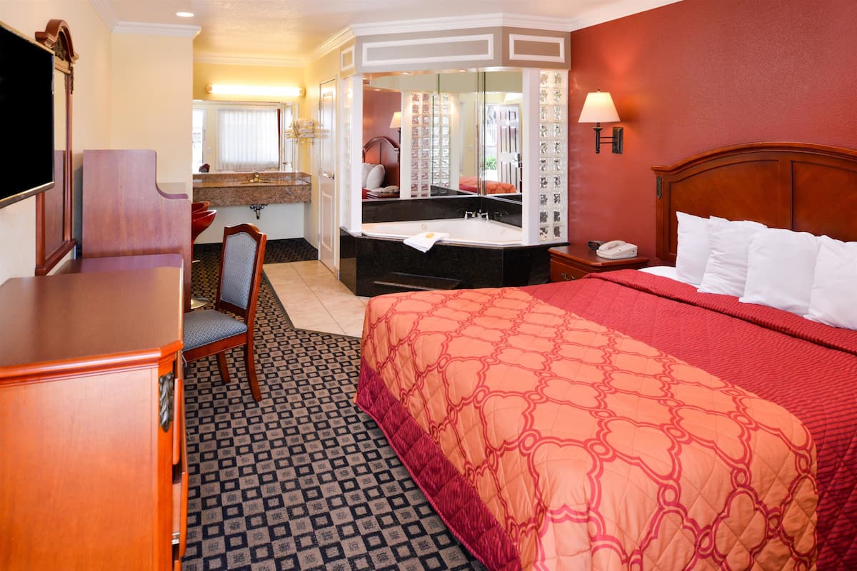 Een hotelkamer met een bed, een bureau, een stoel, een kaptafel met spiegel en een badkamer.