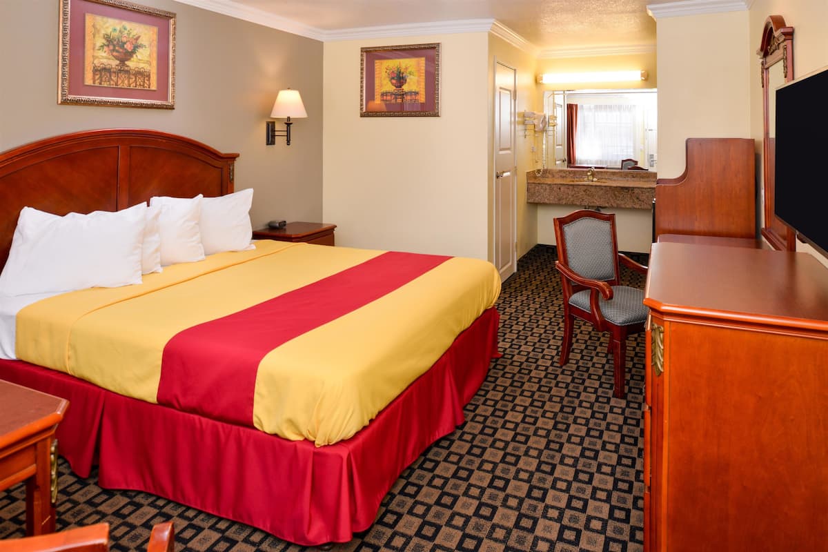 Een hotelkamer met een groot bed, een bureau, een stoel, een televisie en een badkamer zichtbaar door een geopende deur.