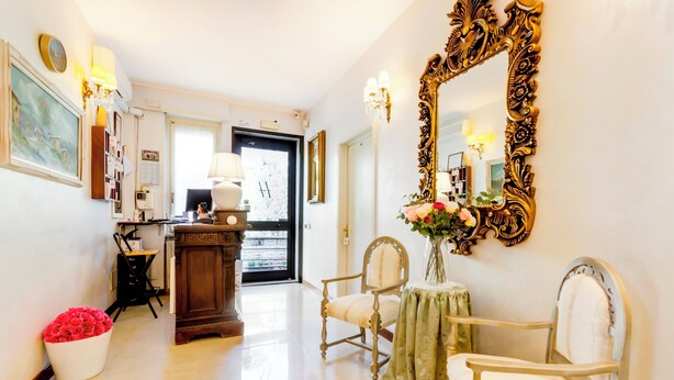 A spacious hotel lobby with a large ornate mirror, a wooden desk, and two chairs. - Hotel Original (Turin)