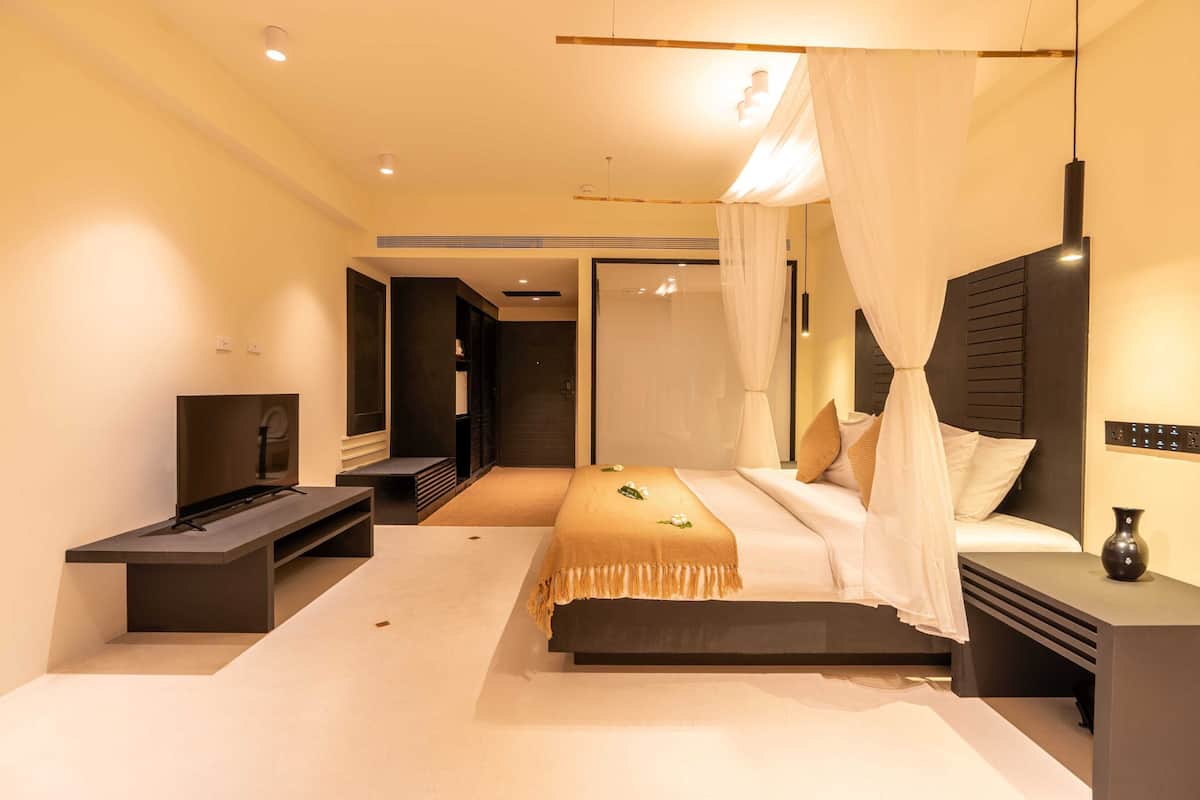 A modern bedroom with a bed, bedside tables, a TV, and a large mirror.