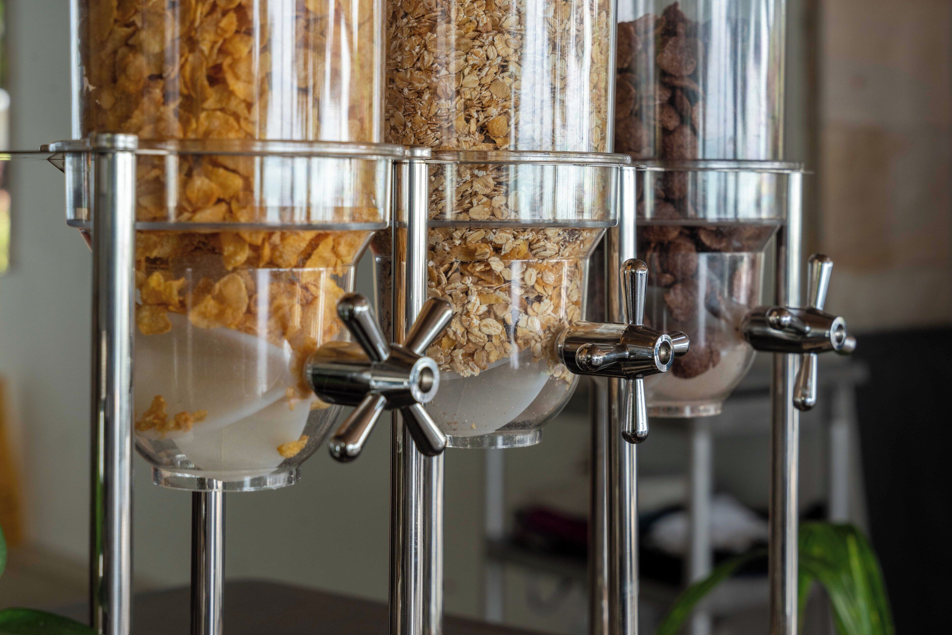 A food dispensing station with multiple containers of granola and other snacks.