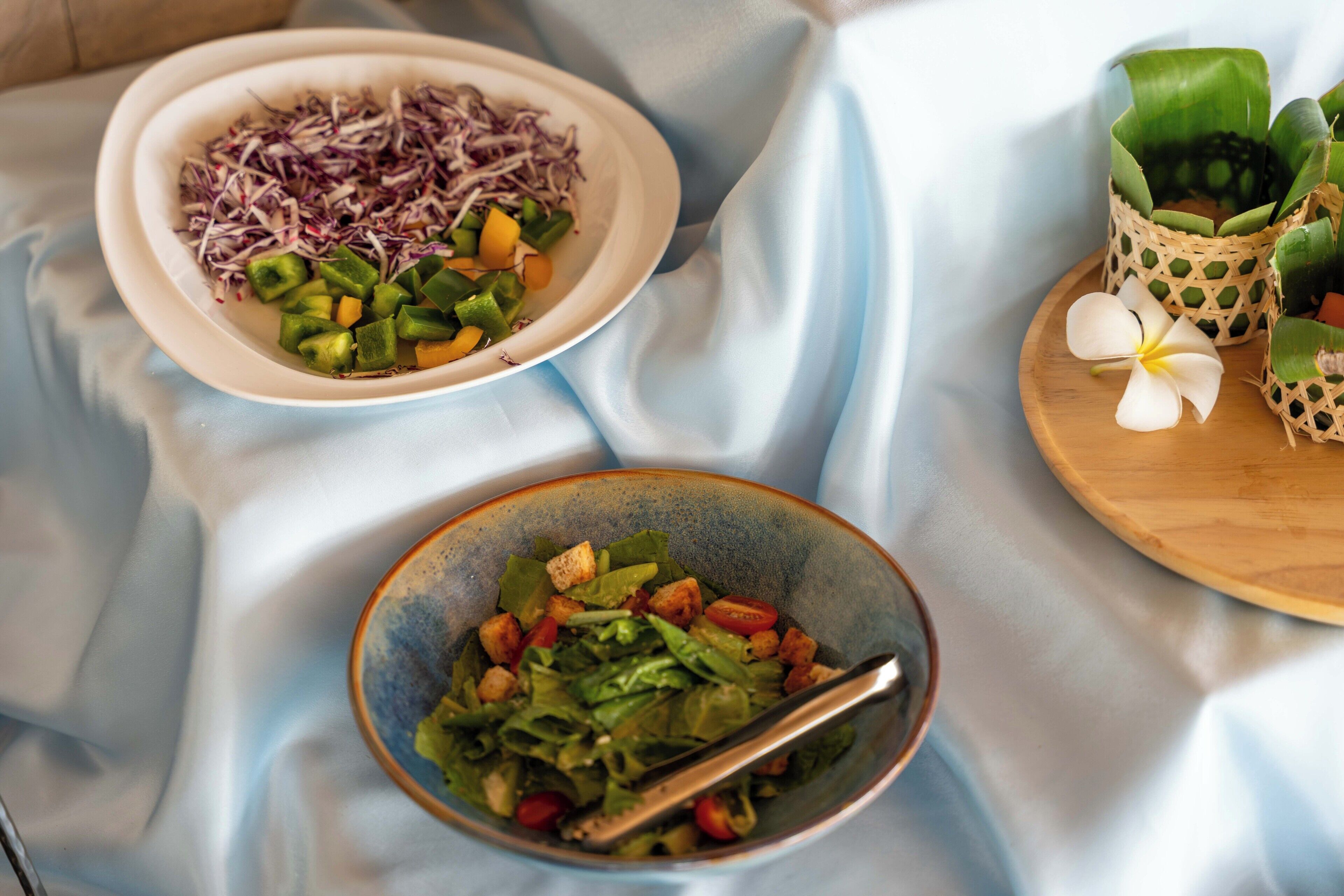 Two bowls of salad on a table with a white cloth.