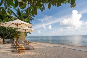 A beach with umbrellas, lounge chairs, and a view of the sea.