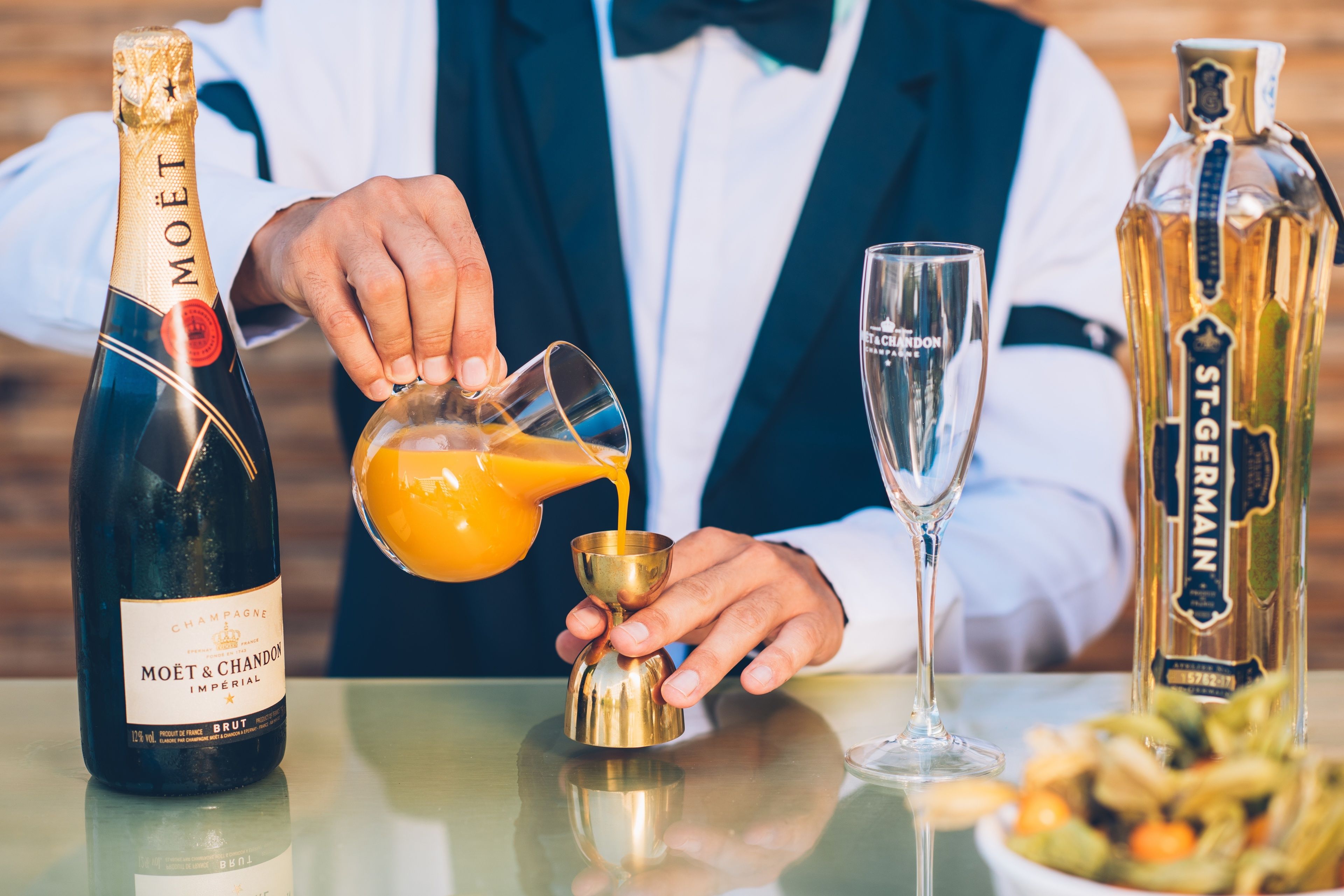 Eine Person gießt einen Drink aus einer Flasche mit der Aufschrift "MOËT & CHANDON" in ein goldenes Karaffe.
