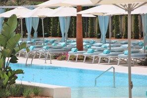 A pool area with lounge chairs and umbrellas, surrounded by greenery. - Iberostar Selection Playa de Palma (Palma de Mallorca)